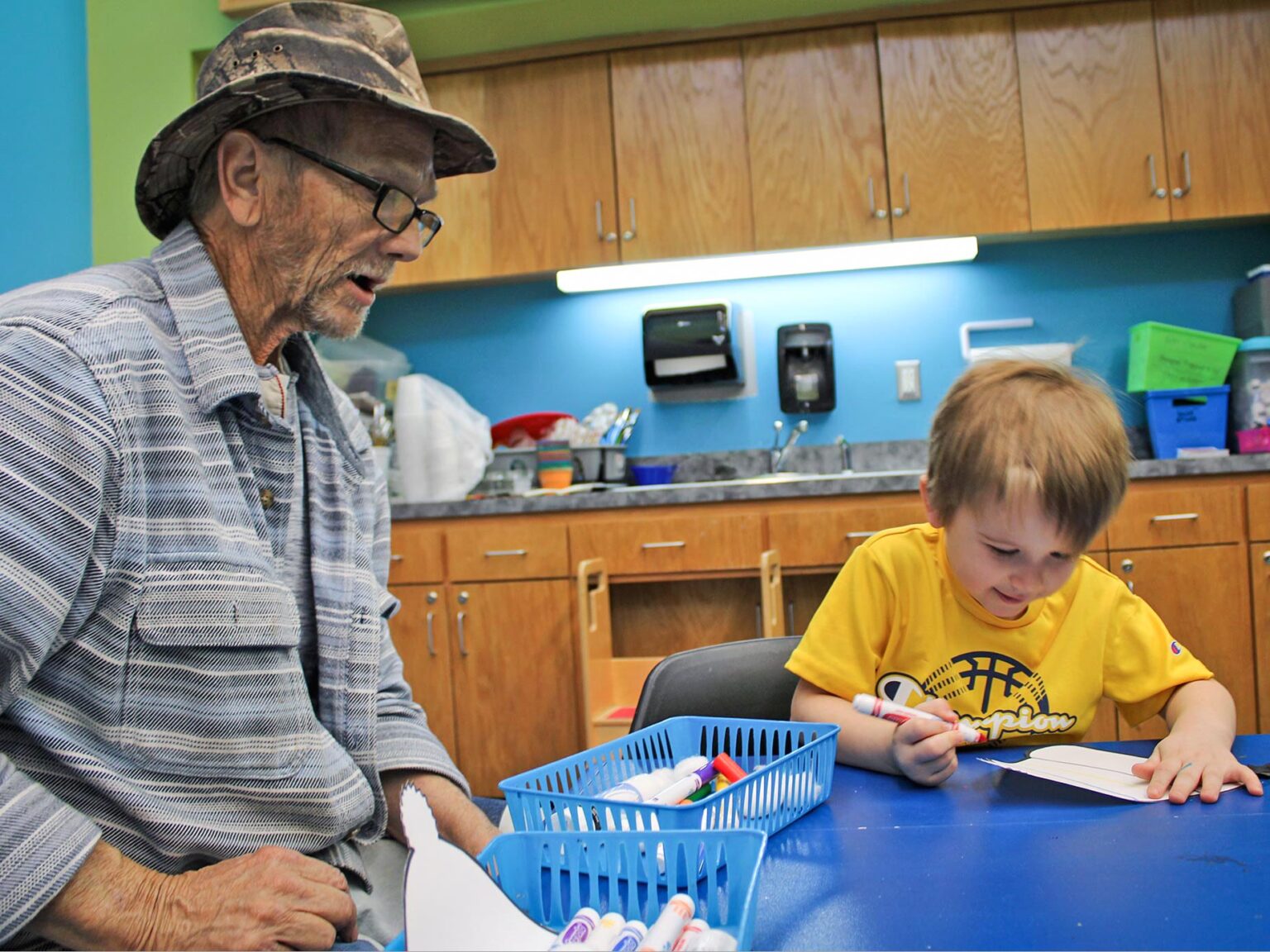Grandfather watching grandson write with marker.