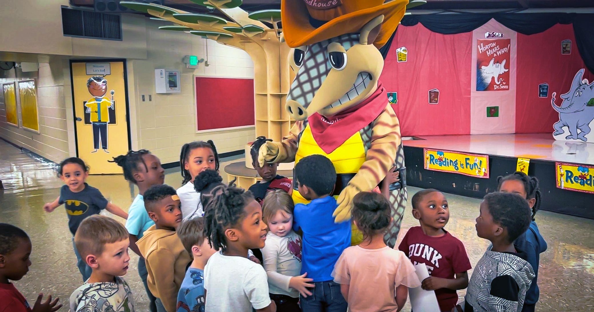 Children surround Andy Armadillo and hug him.