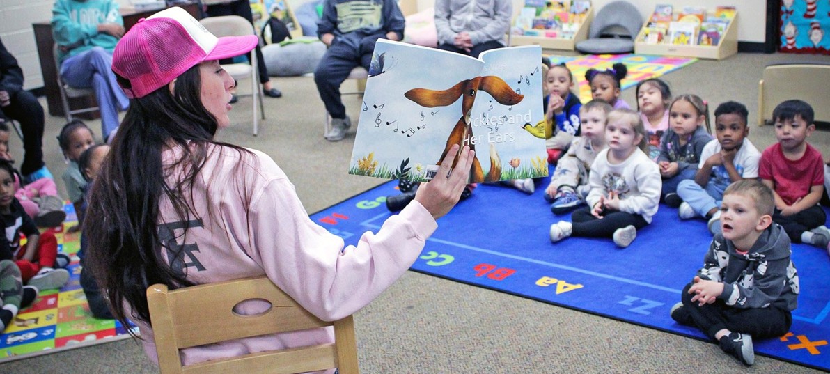 A special guest, dressed in all pink, reads to CSO Head Start students in the library at CSO's Pat Longinotti center.